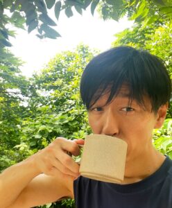 朝の自然光の中でマグカップの飲み物を口にする様子